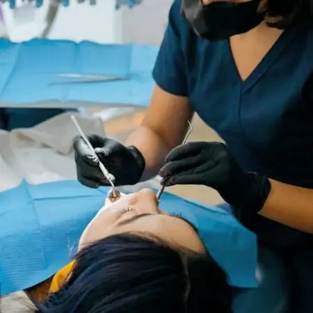 Home Dentist performing dental care procedure on patient in clinic setting.
